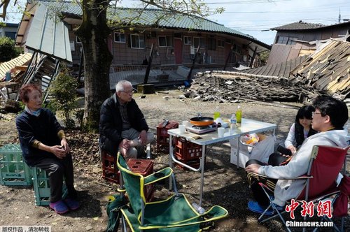 當(dāng)?shù)貢r間4月17日，日本熊本縣震后見聞。一家人圍坐在簡易桌旁吃飯，周圍都是倒塌的房屋。