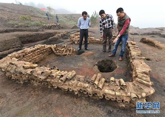 在桐木嶺礦冶遺址，考古人員查看用廢棄坩堝壘筑的房屋遺址（11月18日攝）。