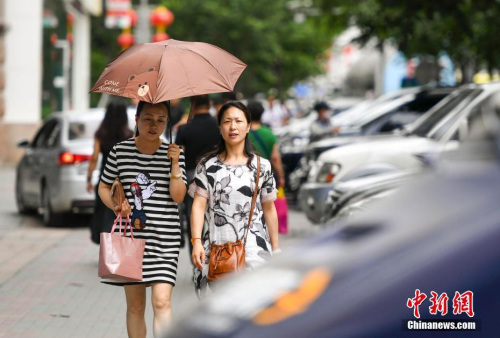 新疆烏魯木齊市街頭，民眾打傘抵擋高溫天氣。