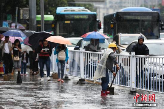 資料圖：行人在雨中出行。 黃芷昕 攝