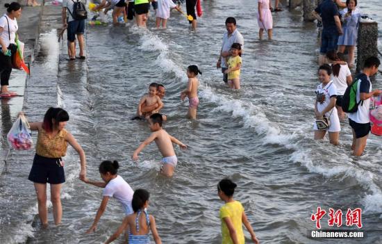 7月4日傍晚，市民們帶著小孩在海邊戲水消暑。連日來，受副熱帶高壓影響廈門地區(qū)持續(xù)高溫。 張斌 攝