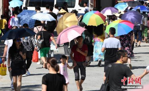 7月12日，廈門一景點(diǎn)游客們紛紛打起傘遮擋烈日。張斌 攝