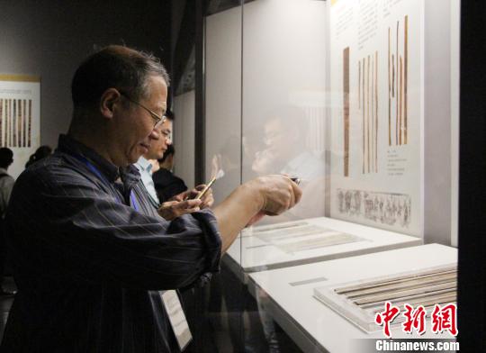 圖為參展觀眾在中國簡帛文化展上觀看和拍攝簡帛文物?！≮w曉　攝