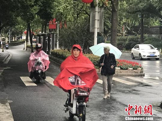 11日，南京迎來(lái)降溫降雨。圖為市民披上雨衣出行?！铑伌?攝