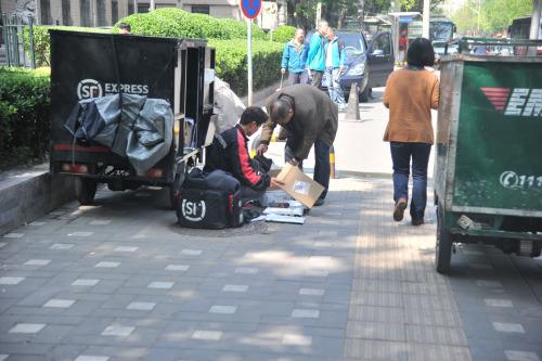 圖為快遞小哥在路邊配送快遞。呂春榮 攝