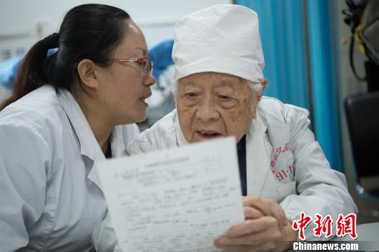 問診時，她的助手王利花趴在于載畿耳朵旁當(dāng)“傳聲筒”，書寫病歷時，于載畿用尺子比著。　武俊杰 攝