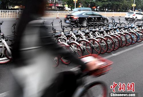 資料圖：路人騎著共享單車經(jīng)過“車堆”。<a target='_blank' href='http://www.chinanews.com/'>中新社</a>記者 張斌 攝