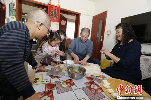 圖為彭秀芳“一家四口”包餃子。(抱著玲玲的是福利院工作人員) 胡貴龍 攝