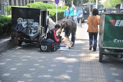 圖為快遞小哥在路邊配送快遞。呂春榮 攝