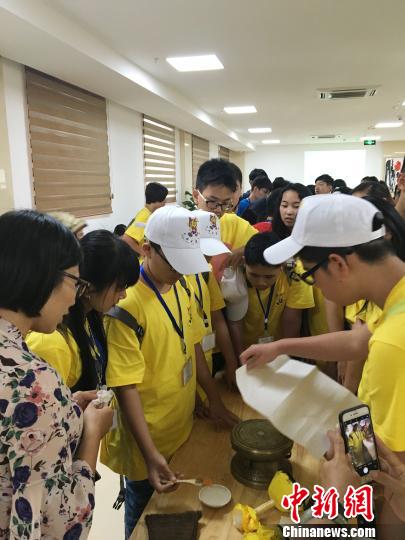 圖為華裔青少年當(dāng)日在廣西自治區(qū)博物館人員的指導(dǎo)下嘗試拓印一面小的銅鼓。鐘建珊 攝