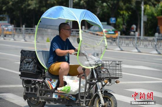 資料圖：男子在電動車上撐起遮陽棚。<a target='_blank' href='http://www.chinanews.com/'>中新社</a>記者 劉文華 攝