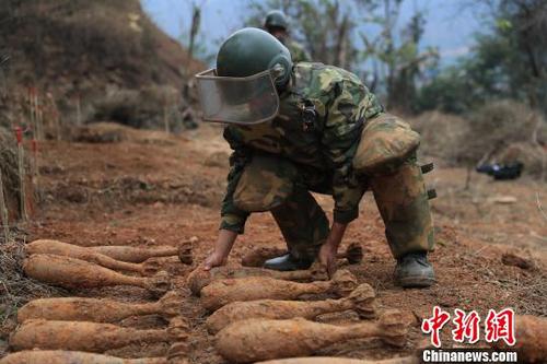 中國人民解放軍南部戰(zhàn)區(qū)陸軍云南掃雷大隊在雷場掃雷期間，一名戰(zhàn)士將一枚搜排出來的炮彈放至臨時存放點?！蠲?攝