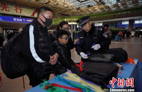 12月28日，北京西站派出所民警為背黑色雙肩包的旅客系上個性小標識，以防在通過安檢或乘車過程中出現(xiàn)錯拿情況。(完) 龐賀雷 攝