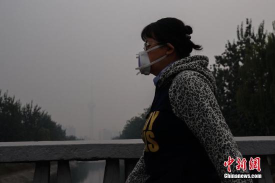 資料圖：北京一名市民戴防霾口罩在戶(hù)外行走，遠(yuǎn)處的中央電視塔亦被霧霾籠罩。<a target='_blank' href='http://www.chinanews.com/'>中新社</a>記者 崔楠 攝