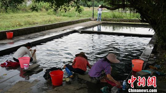 幾名婦女在“雅蔡冷泉”旁一邊聊天一邊洗著衣物。　符宇群 攝