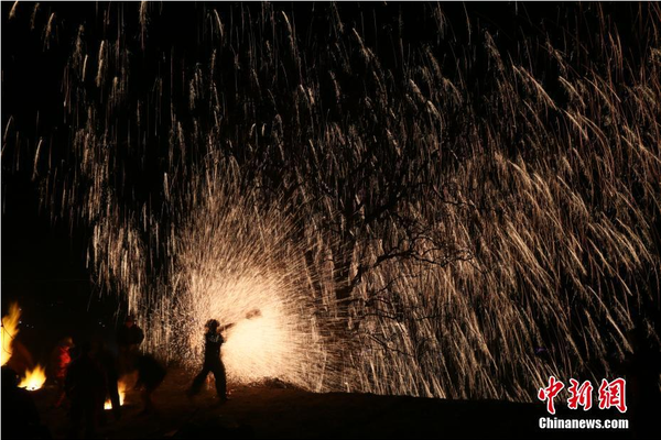 該村“打樹花”的習(xí)俗已延續(xù)了近600年，村民將生鐵融成鐵水后，再用特制的木板將鐵水擊打至樹上，頓時(shí)綻放出萬點(diǎn)“鐵花”。中新社記者 陳昊 攝