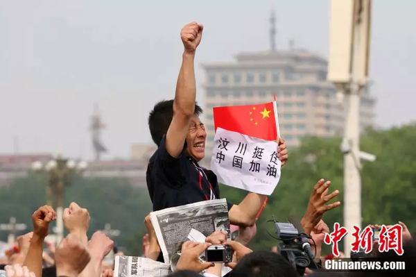 2008年5月19日，北京天安門(mén)廣場(chǎng)上的民眾為地震遇難者默哀，一位來(lái)自四川的男子高舉右手為家鄉(xiāng)加油。中新社記者 富田 攝